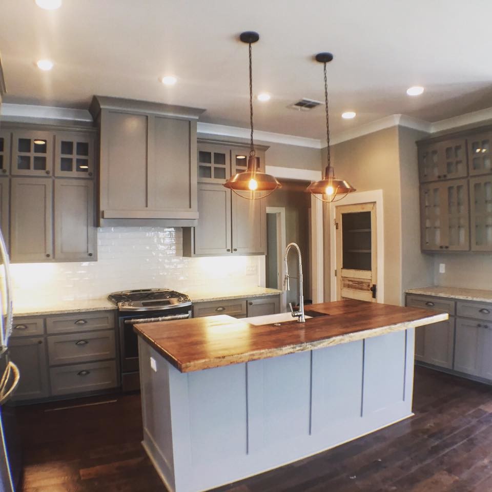 This is an example of a traditional l-shaped kitchen in New Orleans with a belfast sink, white splashback, metro tiled splashback, stainless steel appliances, dark hardwood flooring, recessed-panel cabinets, grey cabinets, granite worktops and an island.