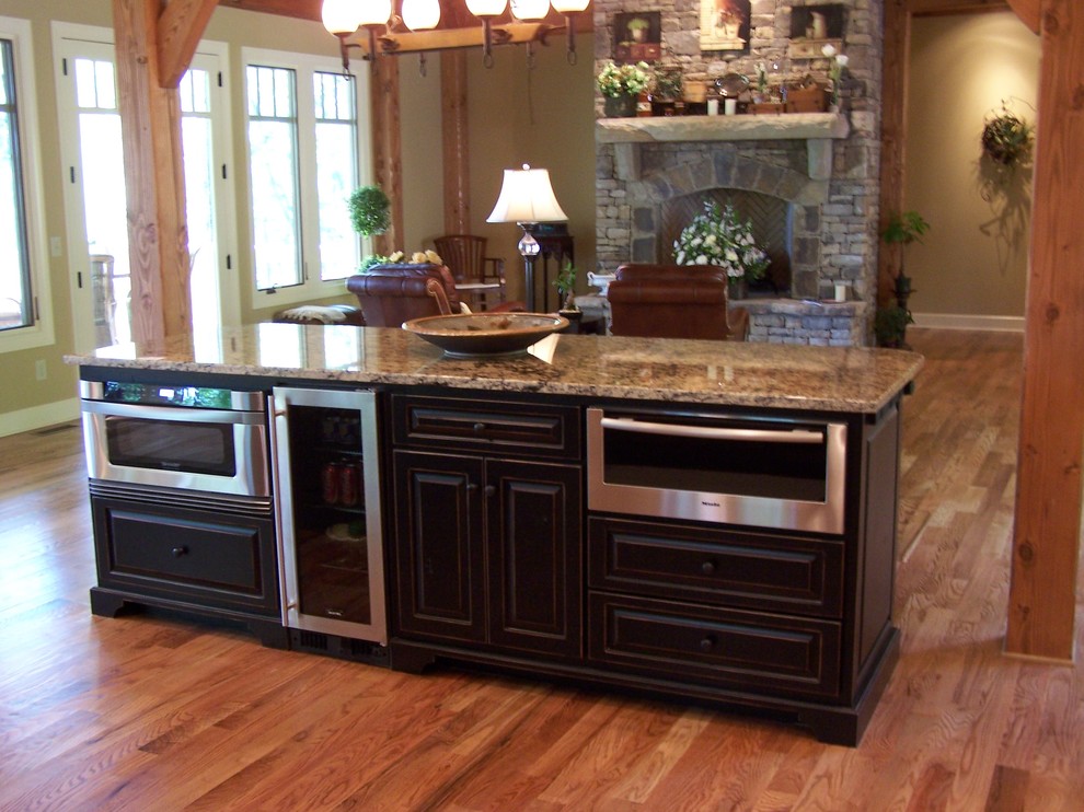 Cette photo montre une cuisine ouverte craftsman en U et bois foncé avec un placard à porte persienne, un plan de travail en granite et un électroménager en acier inoxydable.
