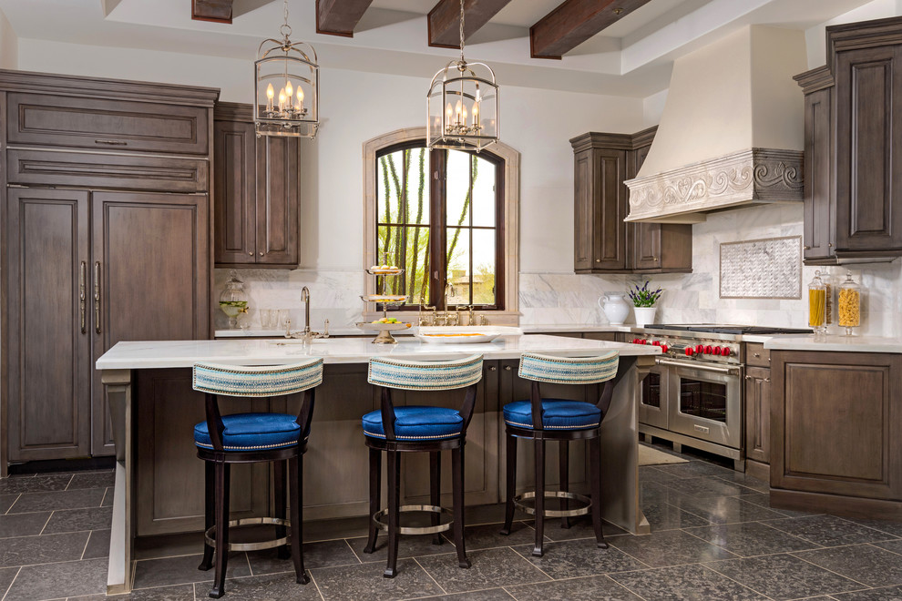 Exempel på ett mycket stort medelhavsstil kök, med en rustik diskho, luckor med upphöjd panel, bruna skåp, marmorbänkskiva, vitt stänkskydd, stänkskydd i stenkakel, rostfria vitvaror, kalkstensgolv och en köksö