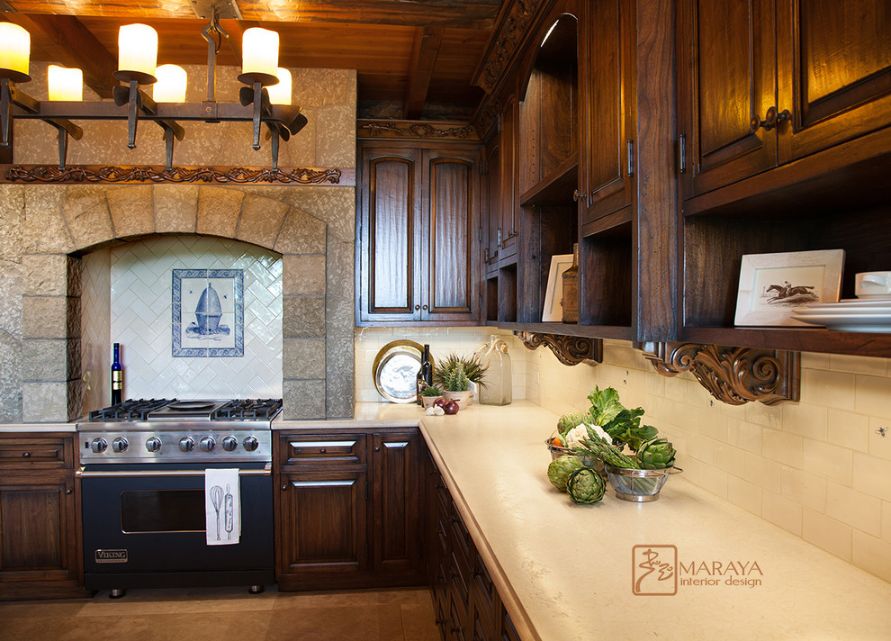 Inredning av ett lantligt mellanstort u-kök, med en rustik diskho, luckor med upphöjd panel, skåp i slitet trä, marmorbänkskiva, vitt stänkskydd, stänkskydd i keramik, integrerade vitvaror och kalkstensgolv