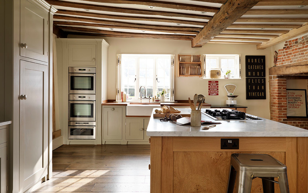 Foto på ett avskilt, stort lantligt kök, med en rustik diskho, skåp i shakerstil, grå skåp, marmorbänkskiva, rostfria vitvaror, mellanmörkt trägolv och en köksö