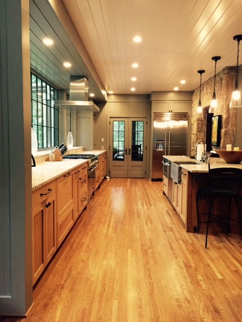 Inspiration for a large farmhouse galley medium tone wood floor open concept kitchen remodel in Other with a farmhouse sink, shaker cabinets, medium tone wood cabinets, limestone countertops, stainless steel appliances and an island