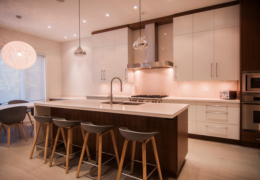 Photo of a large modern u-shaped open plan kitchen in Toronto with a submerged sink, flat-panel cabinets, white cabinets, stainless steel appliances, ceramic flooring, an island, granite worktops, white splashback and stone slab splashback.