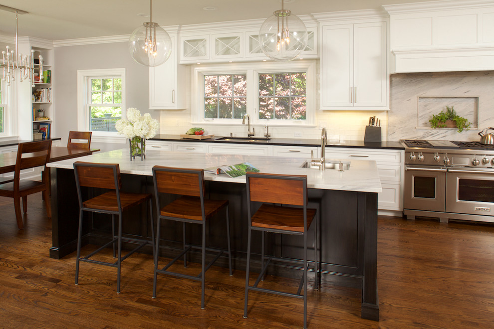 Inspiration for a large timeless u-shaped medium tone wood floor kitchen remodel in New York with an undermount sink, recessed-panel cabinets, white cabinets, quartz countertops, white backsplash, ceramic backsplash, paneled appliances and an island