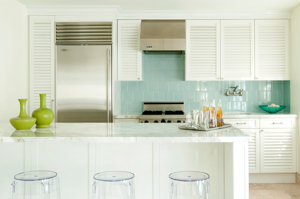 Réalisation d'une cuisine linéaire design avec un électroménager en acier inoxydable, un placard à porte persienne, des portes de placard blanches, une crédence bleue et une crédence en céramique.