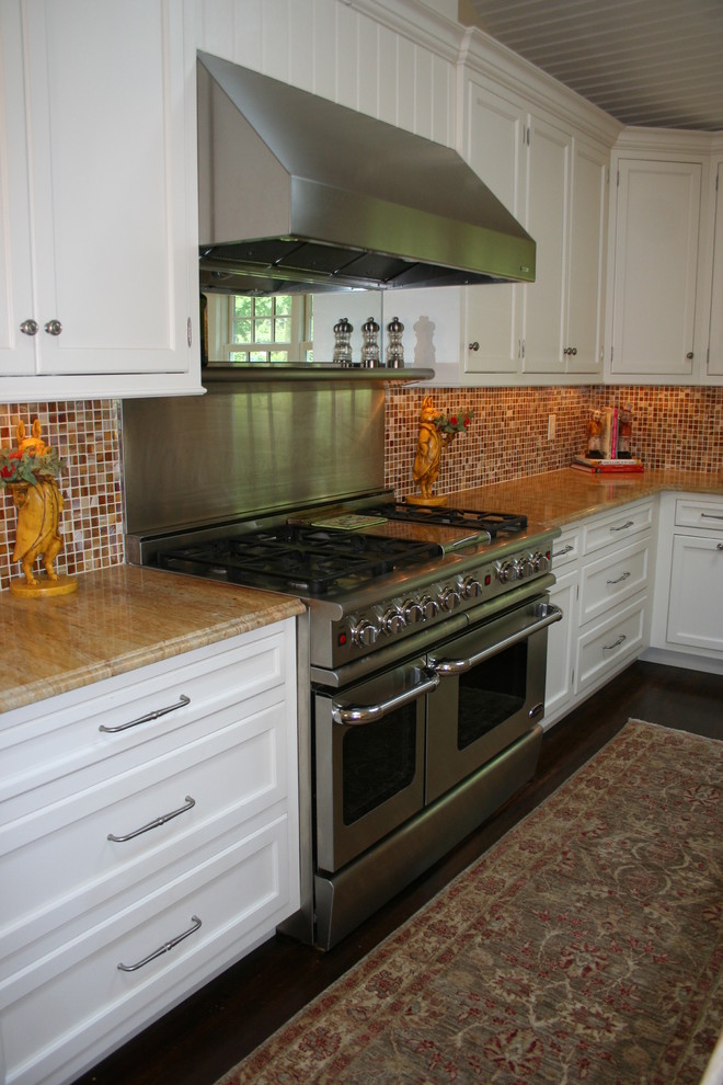 Photo of a medium sized country u-shaped kitchen/diner in New York with a belfast sink, recessed-panel cabinets, white cabinets, granite worktops, stainless steel appliances, dark hardwood flooring and an island.
