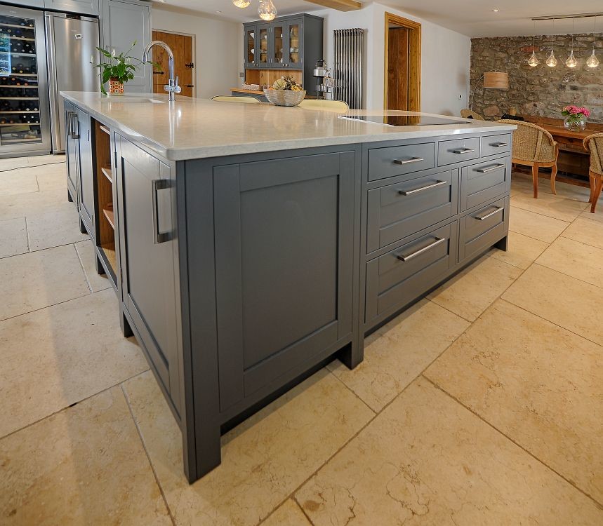 Large rural open plan kitchen in Gloucestershire with a belfast sink, shaker cabinets, grey cabinets, granite worktops, white splashback, stainless steel appliances, porcelain flooring and a breakfast bar.