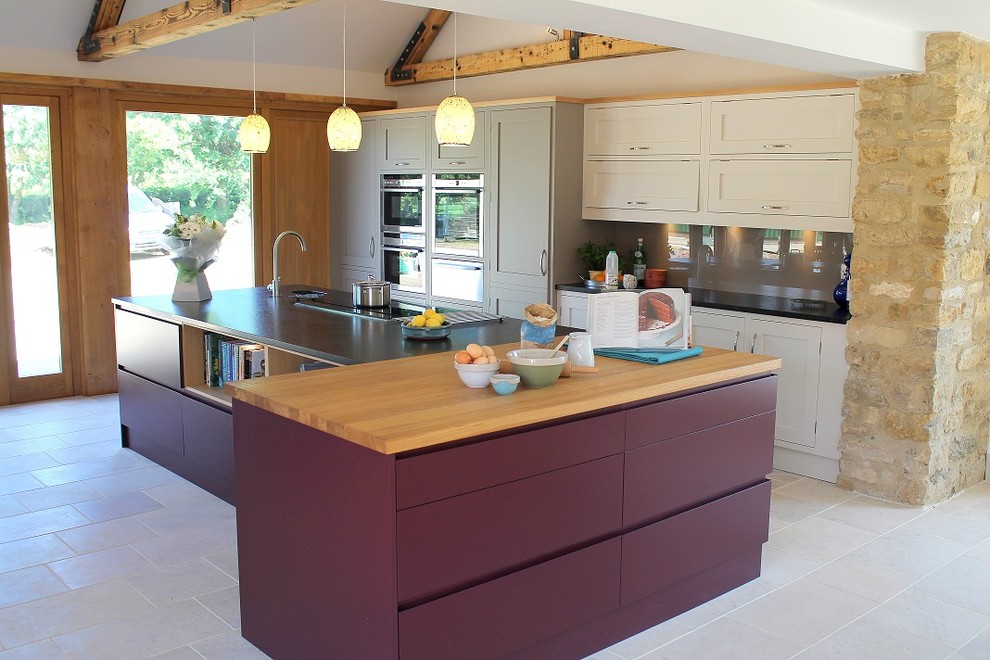 Ejemplo de cocina actual con armarios estilo shaker, puertas de armario beige, salpicadero marrón, salpicadero de vidrio templado y una isla