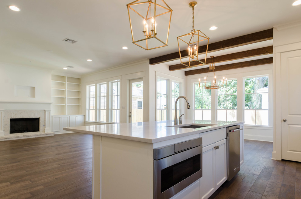 Mid-sized elegant l-shaped medium tone wood floor open concept kitchen photo in New Orleans with an undermount sink, flat-panel cabinets, white cabinets, quartzite countertops, white backsplash, subway tile backsplash, stainless steel appliances and an island