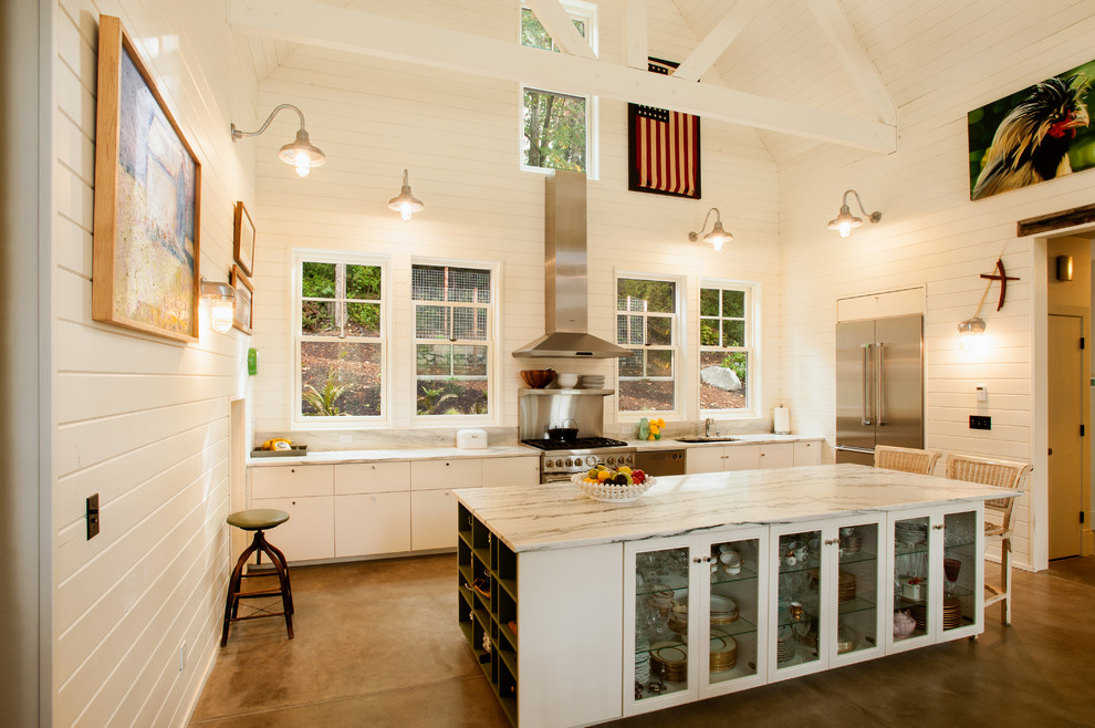 This is an example of a medium sized farmhouse u-shaped open plan kitchen in Seattle with a submerged sink, flat-panel cabinets, white cabinets, quartz worktops, stainless steel appliances, concrete flooring, an island and grey floors.
