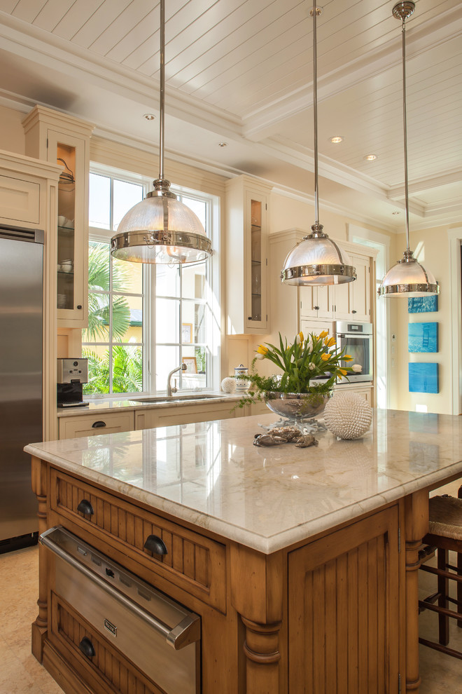 Example of a mid-sized classic single-wall porcelain tile and beige floor enclosed kitchen design in Miami with glass-front cabinets, stainless steel appliances, an undermount sink, white cabinets, glass countertops, white backsplash, wood backsplash and an island