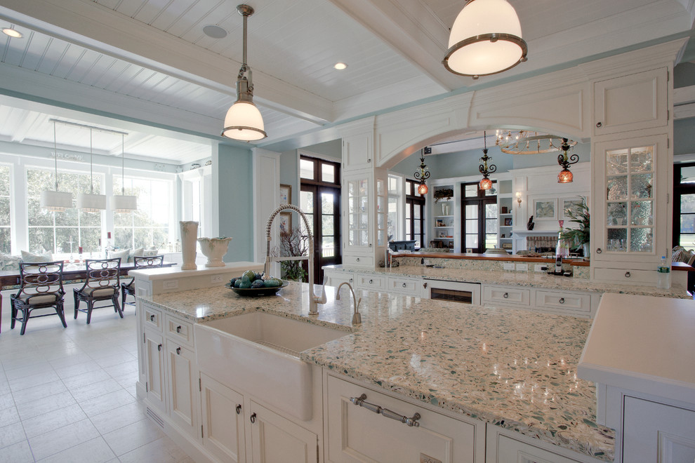 This is an example of a large traditional single-wall kitchen/diner in Charleston with a belfast sink, glass-front cabinets, white cabinets, recycled glass countertops, integrated appliances, ceramic flooring and an island.