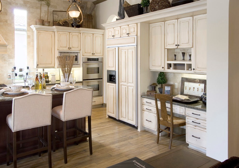 Klassisk inredning av ett avskilt, stort linjärt kök, med en rustik diskho, luckor med upphöjd panel, skåp i slitet trä, granitbänkskiva, brunt stänkskydd, stänkskydd i travertin, integrerade vitvaror, mellanmörkt trägolv, en köksö och brunt golv