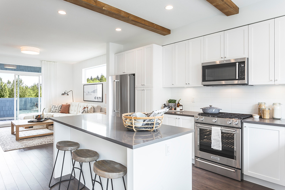 Inspiration for a classic open plan kitchen in Vancouver with shaker cabinets, white cabinets, white splashback, stainless steel appliances, dark hardwood flooring, an island and brown floors.