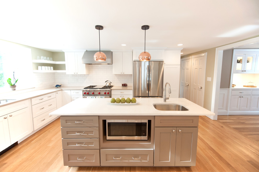 Design ideas for a traditional u-shaped enclosed kitchen in Boston with a double-bowl sink, shaker cabinets, grey cabinets, engineered stone countertops, white splashback, ceramic splashback, stainless steel appliances, light hardwood flooring and an island.