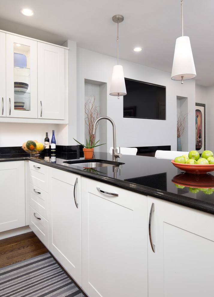 Example of a small transitional u-shaped dark wood floor enclosed kitchen design in DC Metro with shaker cabinets, white cabinets, stainless steel appliances, an undermount sink, quartz countertops and a peninsula