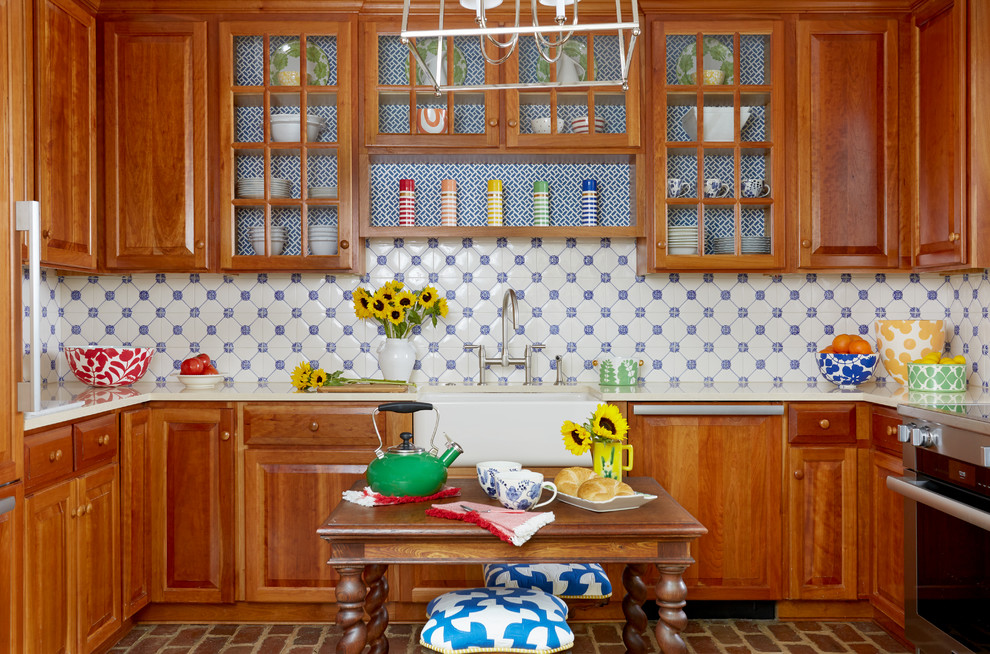 Inredning av ett klassiskt u-kök, med en rustik diskho, skåp i shakerstil, skåp i mellenmörkt trä, blått stänkskydd, stänkskydd i keramik, rostfria vitvaror, tegelgolv och en köksö