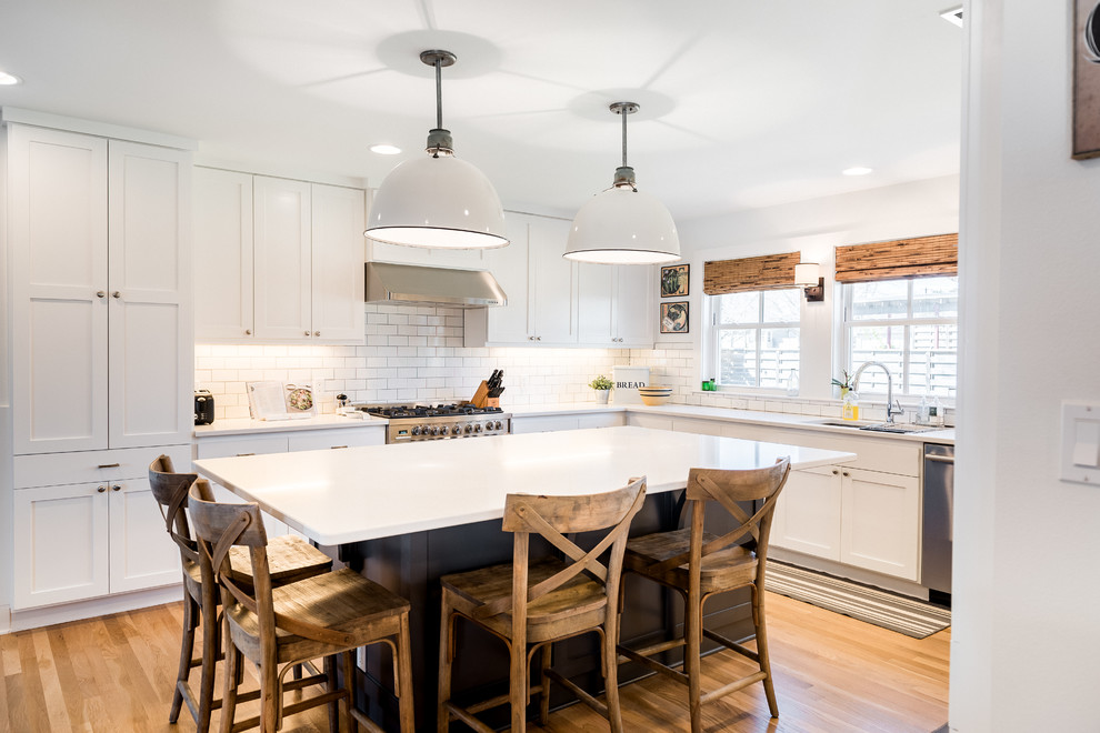 Design ideas for a large traditional u-shaped kitchen/diner in Austin with a double-bowl sink, recessed-panel cabinets, white cabinets, engineered stone countertops, white splashback, metro tiled splashback, stainless steel appliances, medium hardwood flooring and an island.