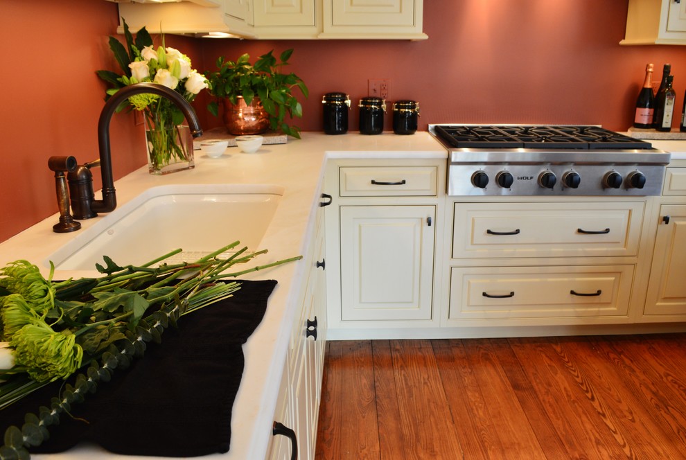 Immagine di una cucina tradizionale di medie dimensioni con ante a filo, ante beige, top in marmo, elettrodomestici in acciaio inossidabile, pavimento in legno massello medio, lavello sottopiano e paraspruzzi arancione