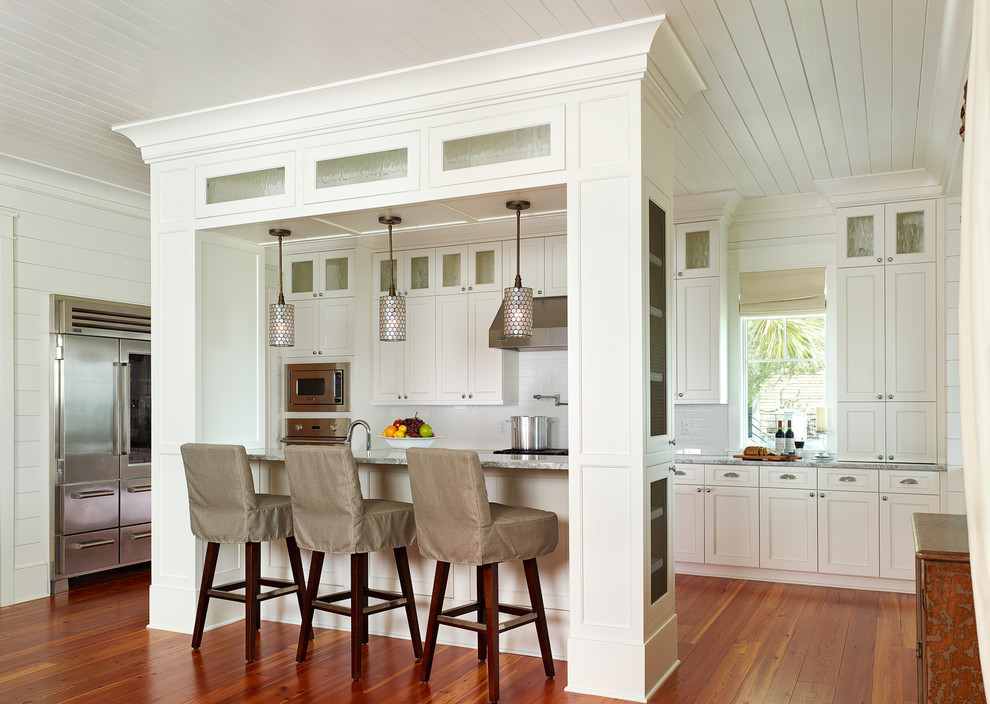 Küche mit Schrankfronten im Shaker-Stil, Küchengeräten aus Edelstahl, weißen Schränken und Küchenrückwand in Weiß in Charleston