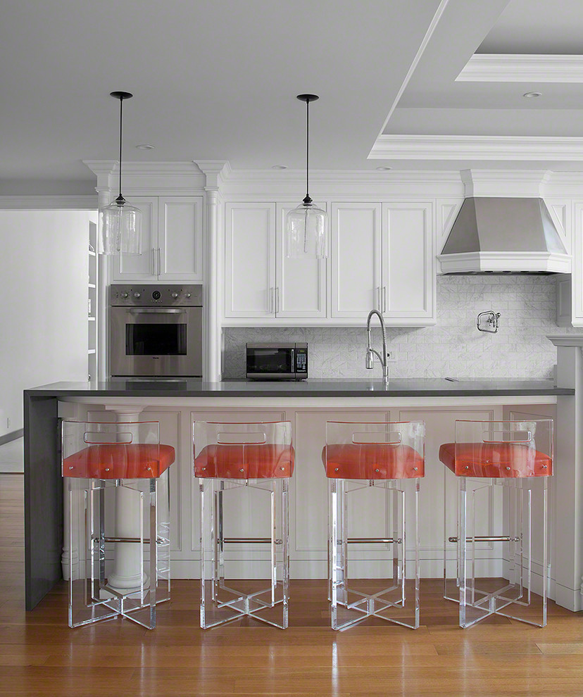 Klassische Küche mit Schrankfronten mit vertiefter Füllung, weißen Schränken, Küchenrückwand in Weiß, Rückwand aus Steinfliesen, braunem Holzboden und Kücheninsel in New York