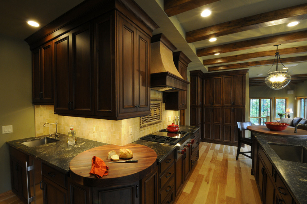 Exempel på ett mycket stort klassiskt kök och matrum, med en rustik diskho, luckor med profilerade fronter, skåp i mörkt trä, granitbänkskiva, beige stänkskydd, stänkskydd i stenkakel, integrerade vitvaror och ljust trägolv