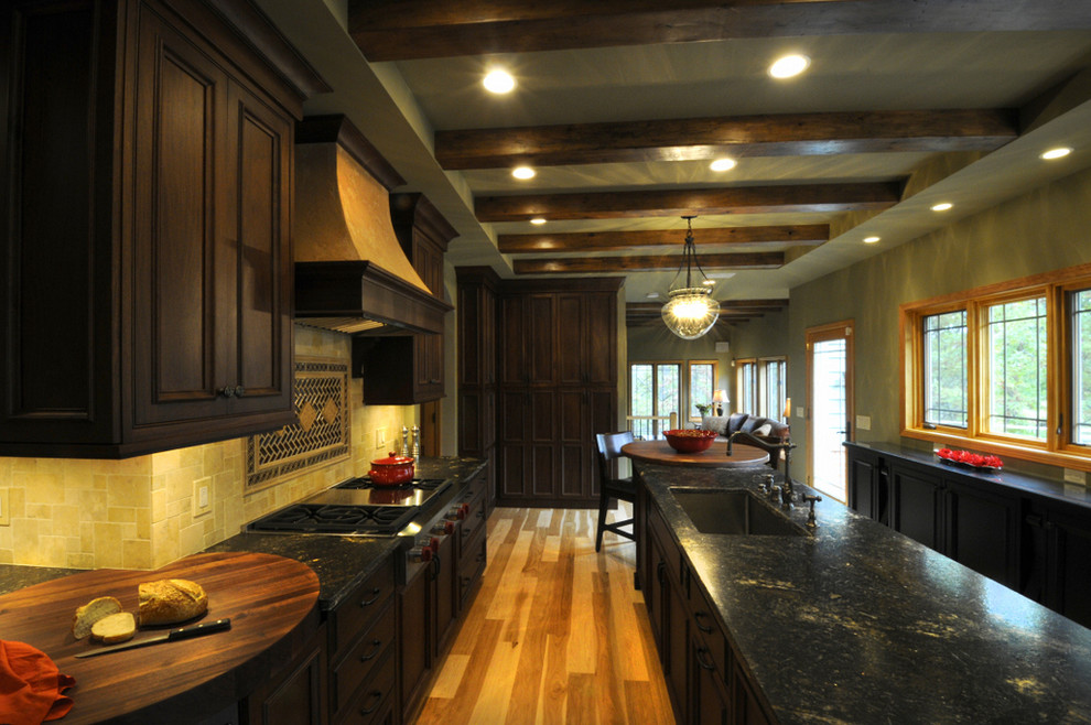 Inredning av ett klassiskt mycket stort kök och matrum, med en rustik diskho, luckor med profilerade fronter, bruna skåp, granitbänkskiva, beige stänkskydd, stänkskydd i stenkakel, integrerade vitvaror och ljust trägolv