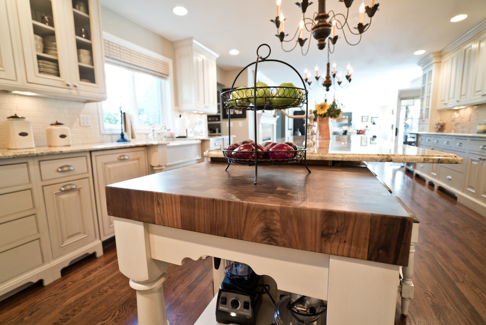 Example of a huge classic u-shaped dark wood floor and brown floor eat-in kitchen design in Denver with a farmhouse sink, raised-panel cabinets, white cabinets, granite countertops, white backsplash, ceramic backsplash, paneled appliances, an island and beige countertops