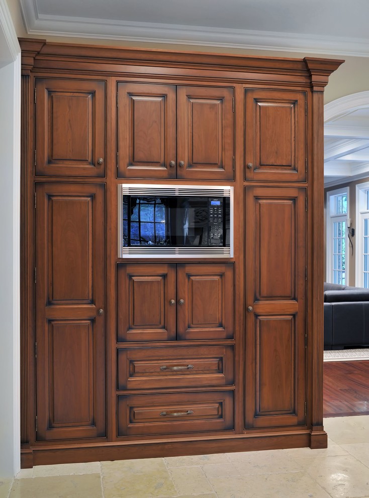 Ejemplo de cocina clásica con armarios con rebordes decorativos, puertas de armario de madera oscura y electrodomésticos de acero inoxidable