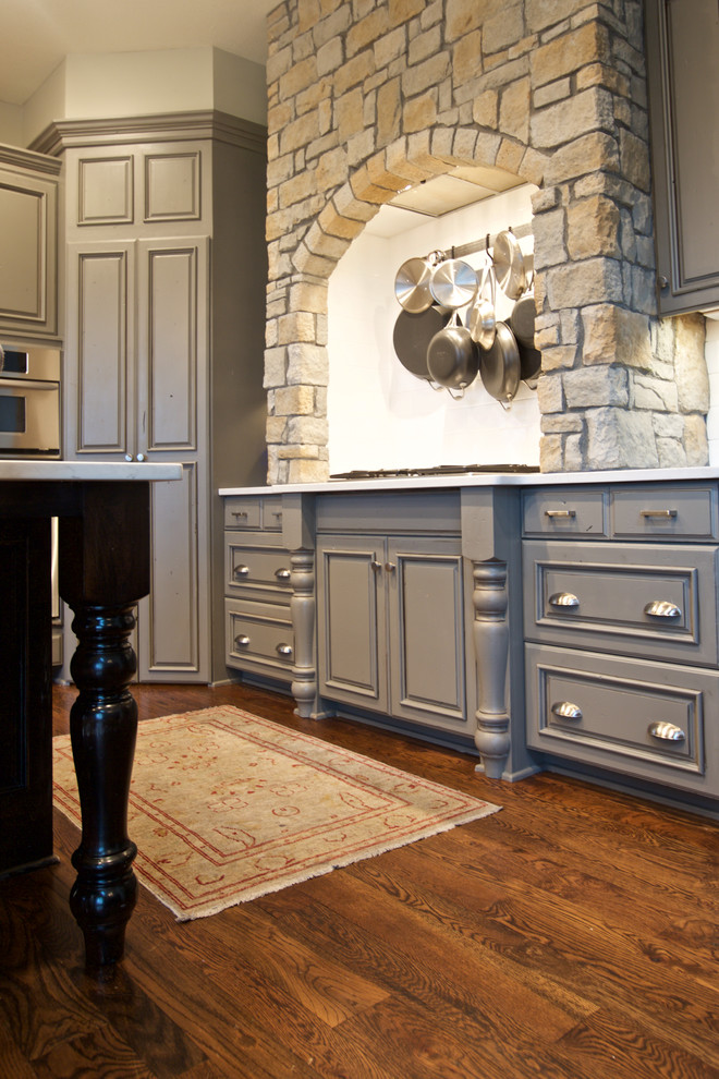 Inspiration for a medium sized traditional l-shaped kitchen in Kansas City with a single-bowl sink, raised-panel cabinets, grey cabinets, granite worktops, integrated appliances, dark hardwood flooring, an island and brown floors.