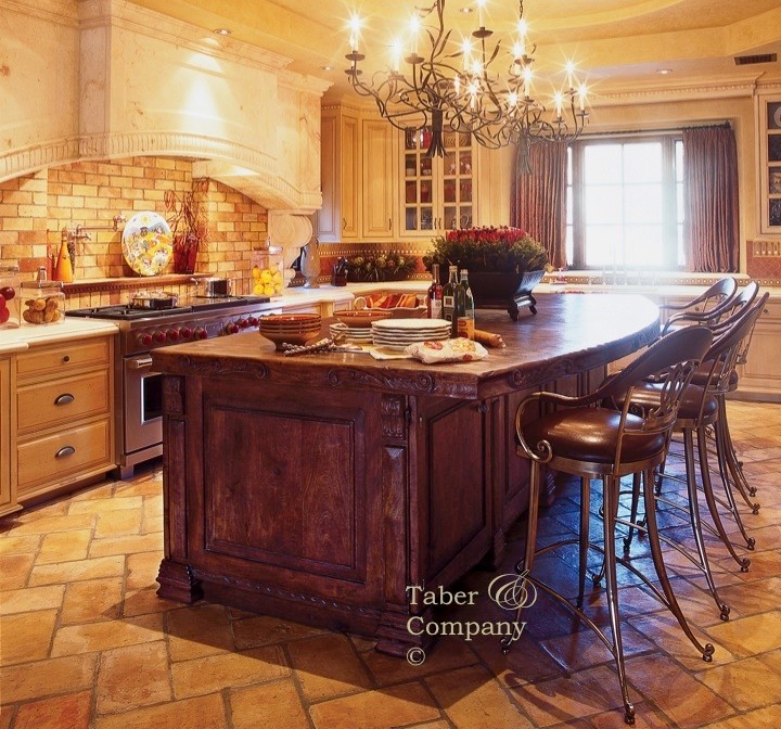 フェニックスにある高級な広い地中海スタイルのおしゃれなアイランドキッチン (エプロンフロントシンク、ヴィンテージ仕上げキャビネット、木材カウンター、セメントタイルのキッチンパネル、レンガの床) の写真