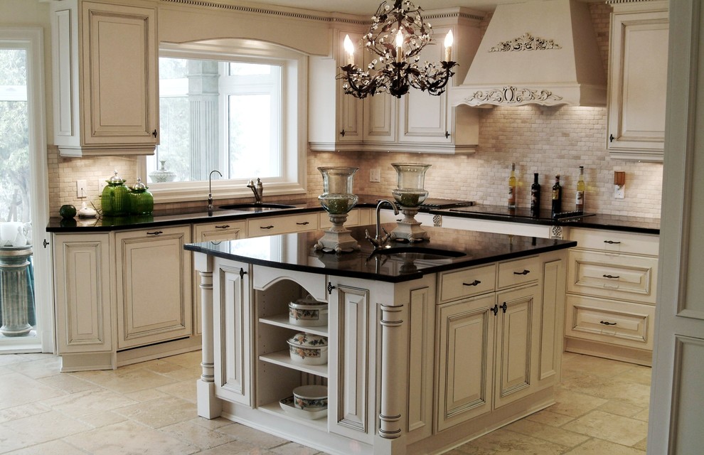 Inredning av ett klassiskt mellanstort kök, med en undermonterad diskho, luckor med upphöjd panel, vita skåp, granitbänkskiva, flerfärgad stänkskydd, stänkskydd i stenkakel, integrerade vitvaror, travertin golv och en köksö