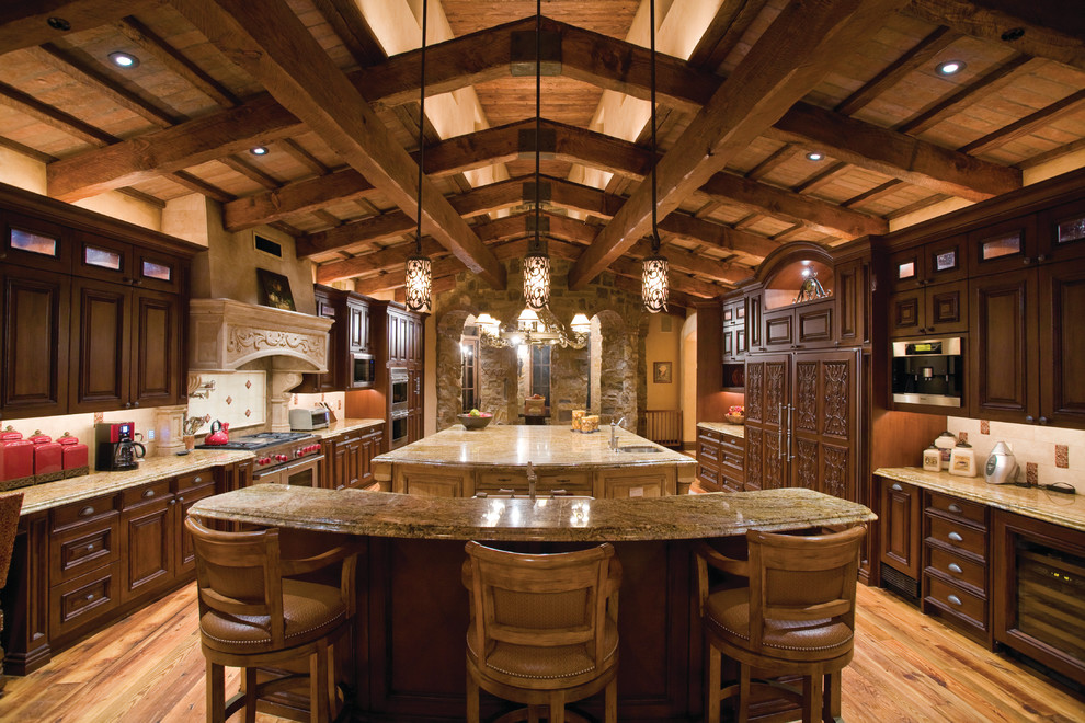 Example of a tuscan u-shaped kitchen design in Phoenix with an undermount sink, raised-panel cabinets, dark wood cabinets, multicolored backsplash and paneled appliances