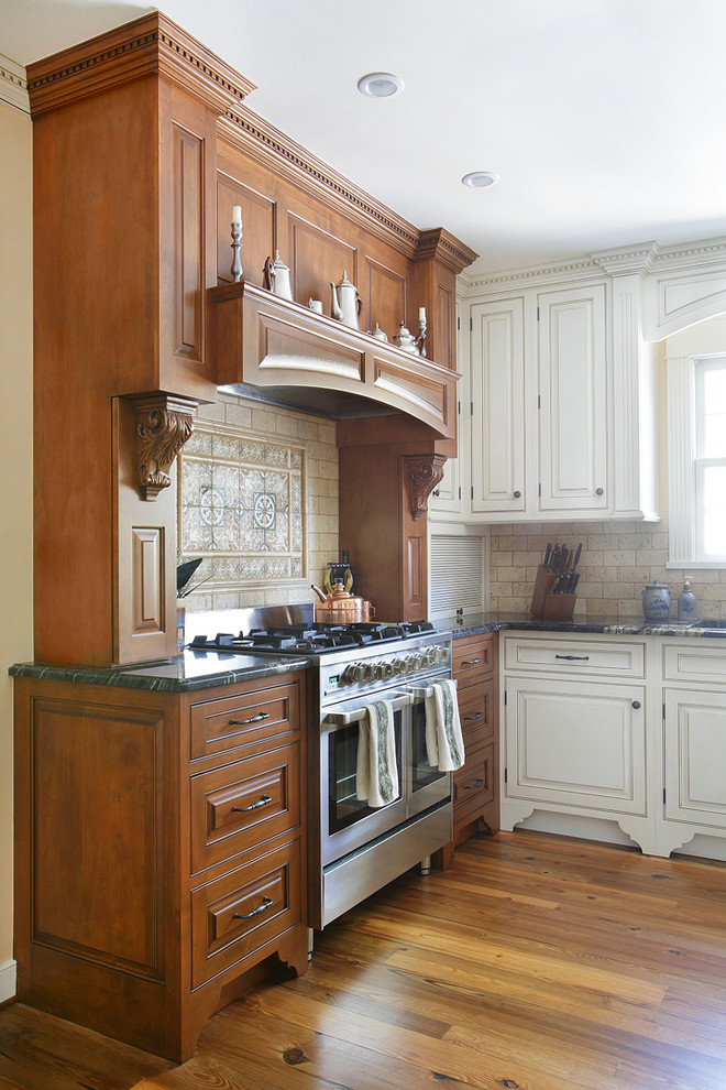 Bild på ett stort vintage kök och matrum, med mellanmörkt trägolv, en undermonterad diskho, luckor med profilerade fronter, skåp i mellenmörkt trä, granitbänkskiva, beige stänkskydd, stänkskydd i stenkakel, rostfria vitvaror och en köksö