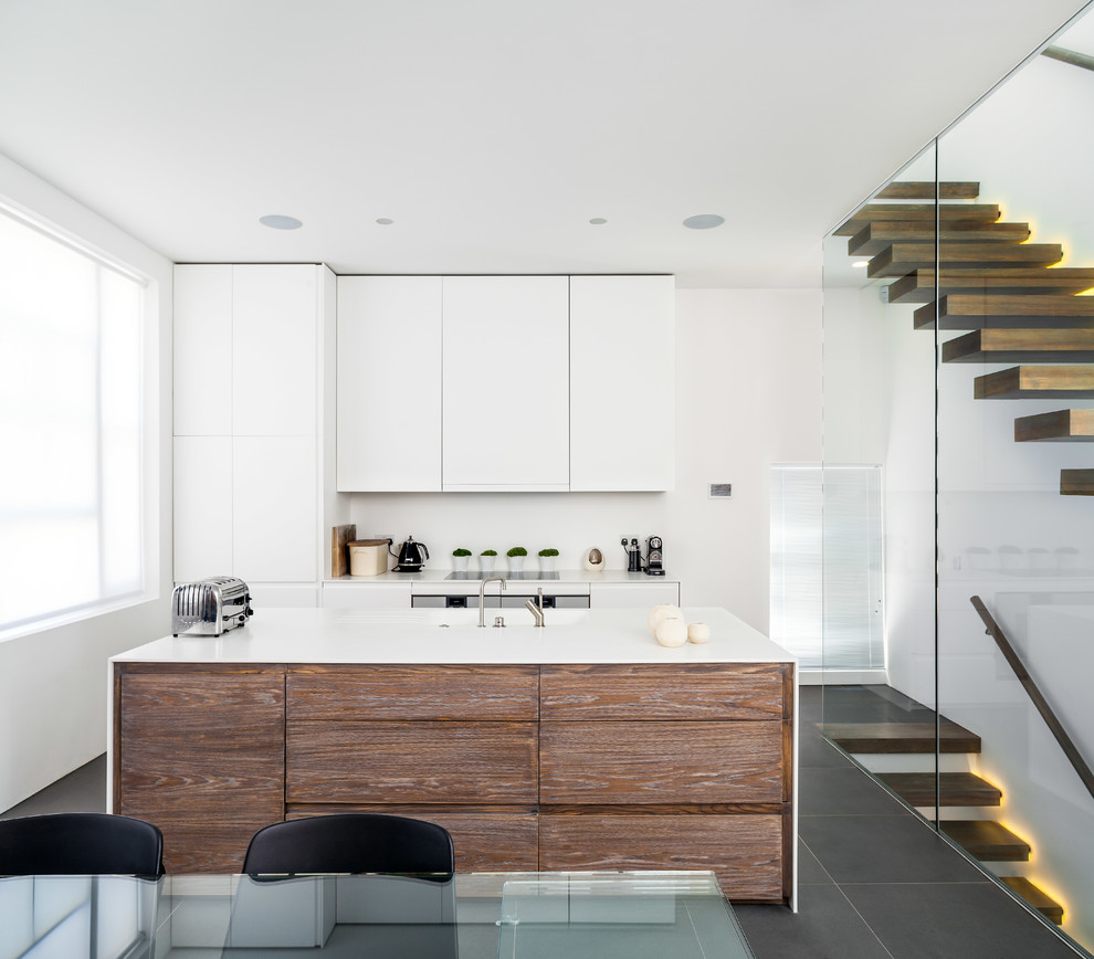 Zweizeilige Moderne Wohnküche mit flächenbündigen Schrankfronten, weißen Schränken, Schieferboden und Kücheninsel in London