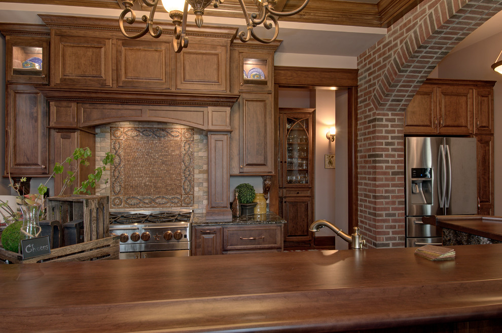Bild på ett avskilt, mellanstort amerikanskt u-kök, med en undermonterad diskho, luckor med upphöjd panel, skåp i mellenmörkt trä, bänkskiva i kvartsit, beige stänkskydd, stänkskydd i mosaik, rostfria vitvaror, mellanmörkt trägolv, en halv köksö och brunt golv