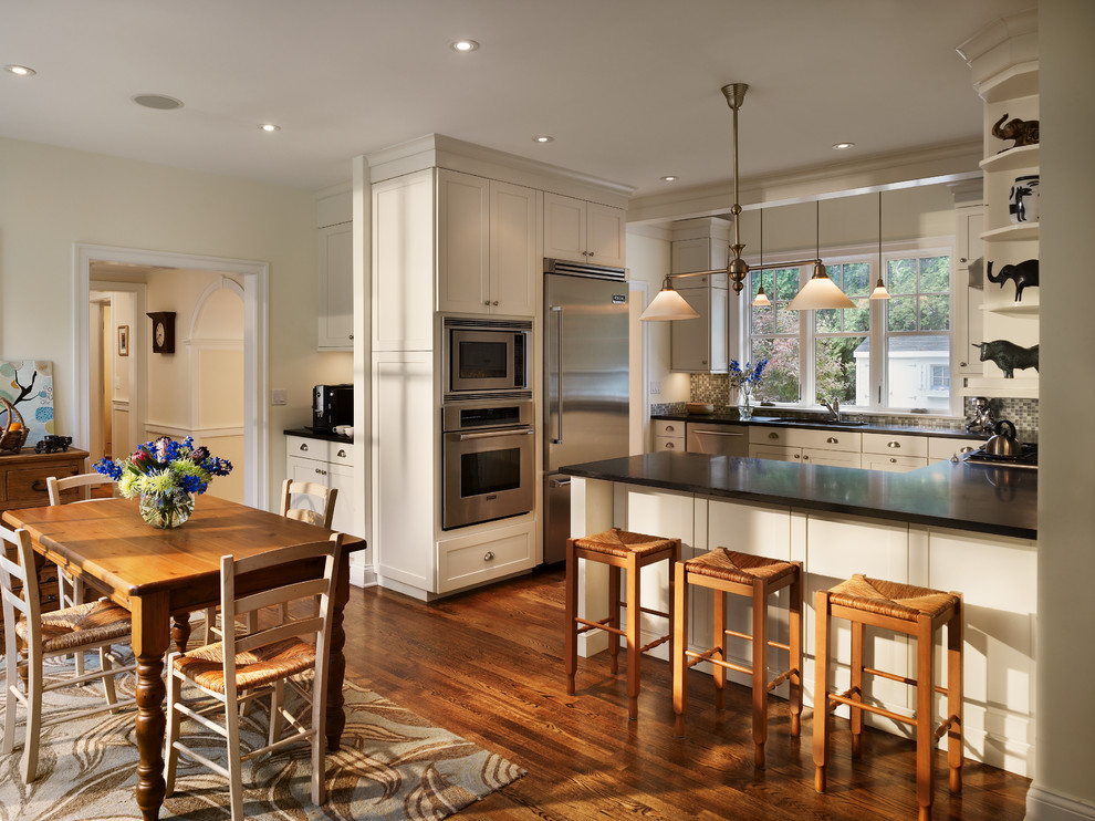 Aménagement d'une cuisine américaine classique en U avec un placard à porte shaker, une crédence en mosaïque et un sol en bois brun.