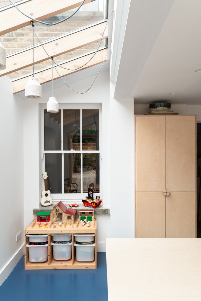 На фото: кухня в скандинавском стиле с светлыми деревянными фасадами, столешницей из нержавеющей стали и синим полом с