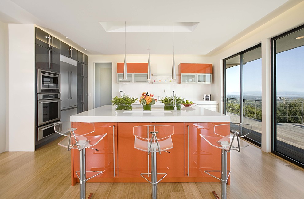 Example of a trendy bamboo floor kitchen design in San Francisco with stainless steel appliances, flat-panel cabinets and orange cabinets