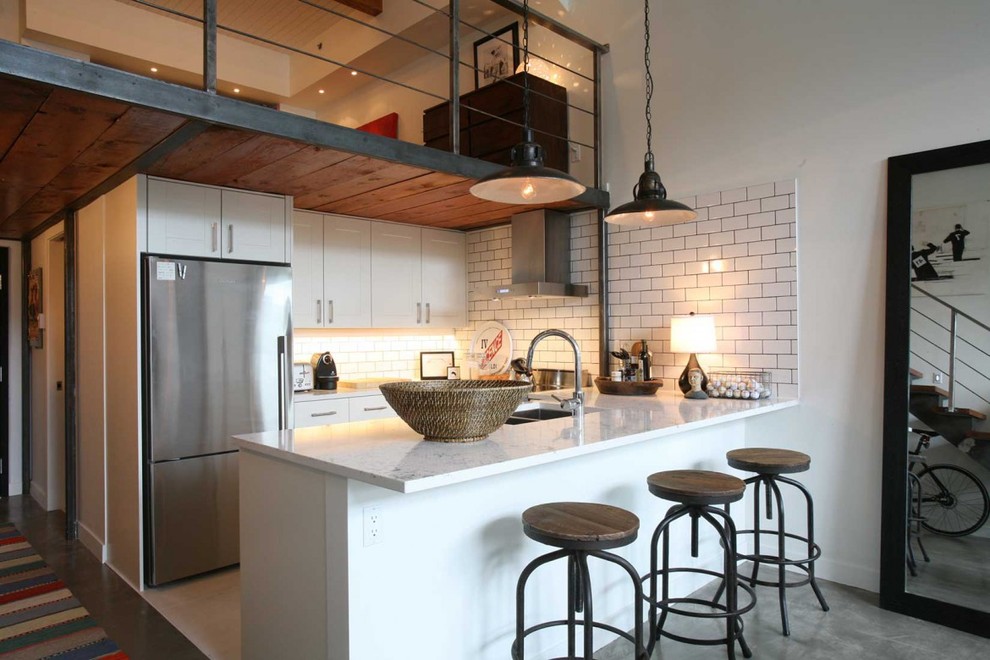 Идея дизайна: п-образная кухня-гостиная в стиле лофт с двойной мойкой, плоскими фасадами, белыми фасадами, белым фартуком, фартуком из плитки кабанчик и техникой из нержавеющей стали