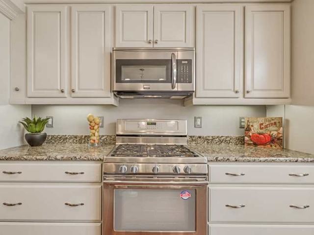 Esempio di una cucina chic con lavello da incasso, ante con bugna sagomata, elettrodomestici in acciaio inossidabile e pavimento in legno massello medio