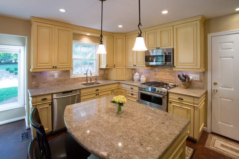 Large traditional u-shaped kitchen in DC Metro with a single-bowl sink, yellow cabinets, beige splashback, stone tiled splashback, stainless steel appliances, raised-panel cabinets, quartz worktops, cork flooring, an island and brown floors.