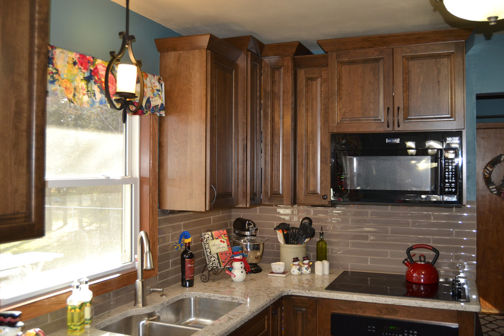 Inredning av ett klassiskt mellanstort kök, med en dubbel diskho, luckor med upphöjd panel, skåp i mörkt trä, bänkskiva i kvarts, beige stänkskydd, stänkskydd i glaskakel, svarta vitvaror, mellanmörkt trägolv och en halv köksö