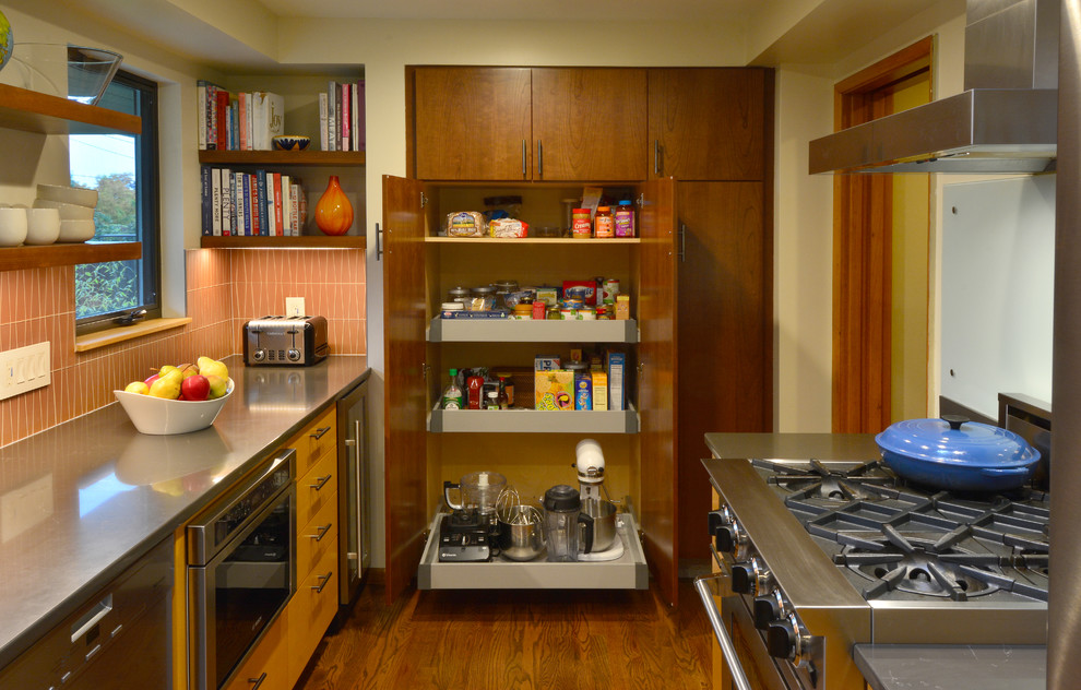 Mid-sized 1950s galley medium tone wood floor eat-in kitchen photo in Seattle with a drop-in sink, flat-panel cabinets, medium tone wood cabinets, quartz countertops, orange backsplash, glass tile backsplash, stainless steel appliances and brown countertops