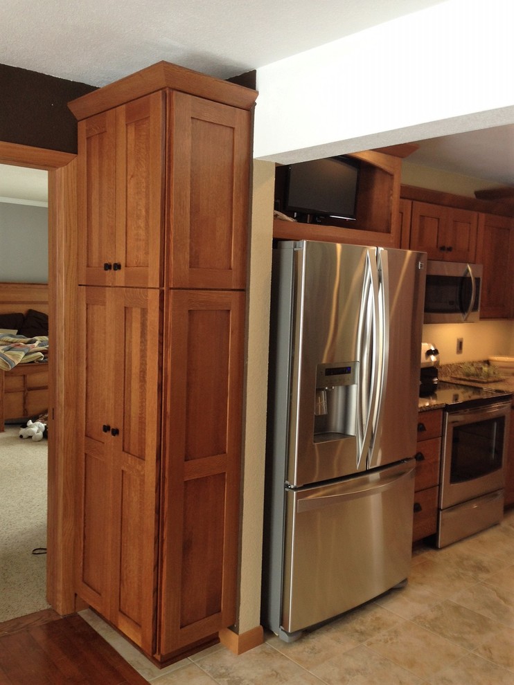 This is an example of a medium sized classic l-shaped kitchen/diner in Cedar Rapids with an island, a submerged sink, shaker cabinets, medium wood cabinets, quartz worktops, brown splashback, stainless steel appliances, laminate floors and beige floors.