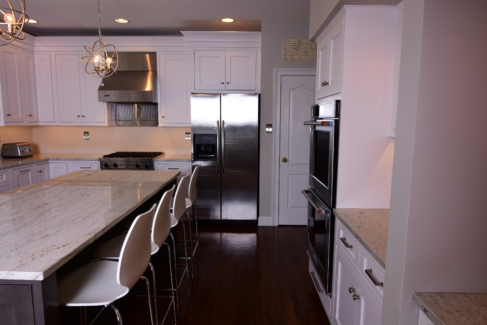Large contemporary u-shaped kitchen/diner in Philadelphia with a submerged sink, recessed-panel cabinets, white cabinets, granite worktops, grey splashback, stainless steel appliances, medium hardwood flooring and an island.