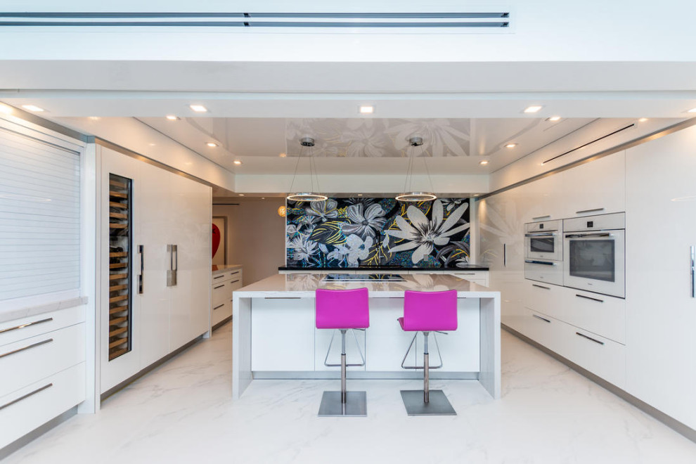Example of a large minimalist u-shaped marble floor and white floor eat-in kitchen design in Miami with an undermount sink, flat-panel cabinets, white cabinets, quartz countertops, multicolored backsplash, mosaic tile backsplash, white appliances, an island and white countertops