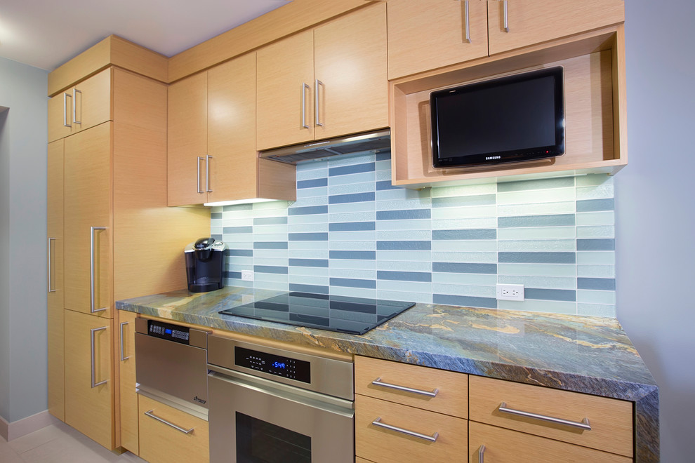 Design ideas for a small contemporary galley kitchen/diner in San Diego with a single-bowl sink, flat-panel cabinets, light wood cabinets, granite worktops, blue splashback, glass tiled splashback, stainless steel appliances, travertine flooring and a breakfast bar.