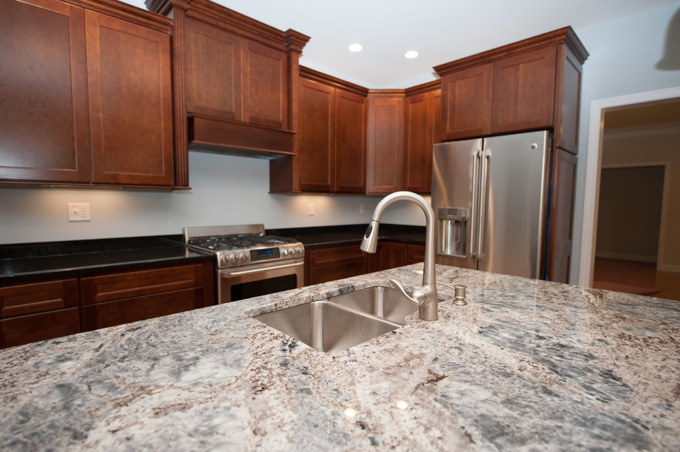 Example of a large classic light wood floor eat-in kitchen design in New York with a double-bowl sink, recessed-panel cabinets, dark wood cabinets, granite countertops, stainless steel appliances and an island