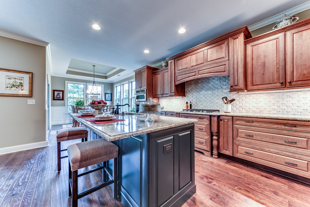 Inspiration for a large timeless galley medium tone wood floor eat-in kitchen remodel in Other with a drop-in sink, beaded inset cabinets, medium tone wood cabinets, granite countertops, white backsplash, porcelain backsplash, stainless steel appliances and an island